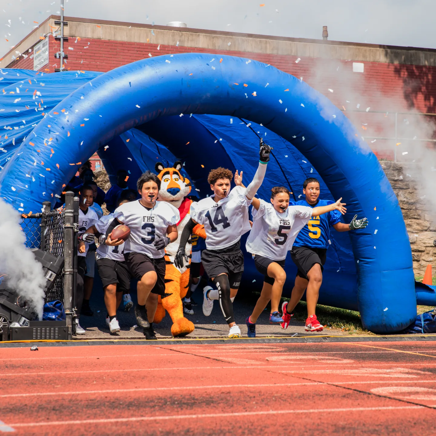 Team running out of a branded inflatable tunnel